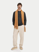 Man wearing a mustard yellow scarf, dark shirt, beige pants, and shoes on a white background. #color_golden-brown #ai-image