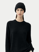 Woman wearing a black headscarf and black sweater on a white background