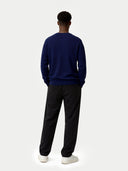 Person wearing a navy sweater and black pants on a white background