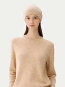 Woman wearing a beige headscarf and sweater against a white background