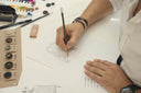 A GOBI designer sketching a knitwear pattern beside buttons and pencils