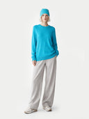 Person wearing a blue sweater and gray pants on a white background #color_peacock-blue
