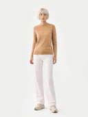 Person wearing a beige sweater and white pants on a white background #color_sheepskin