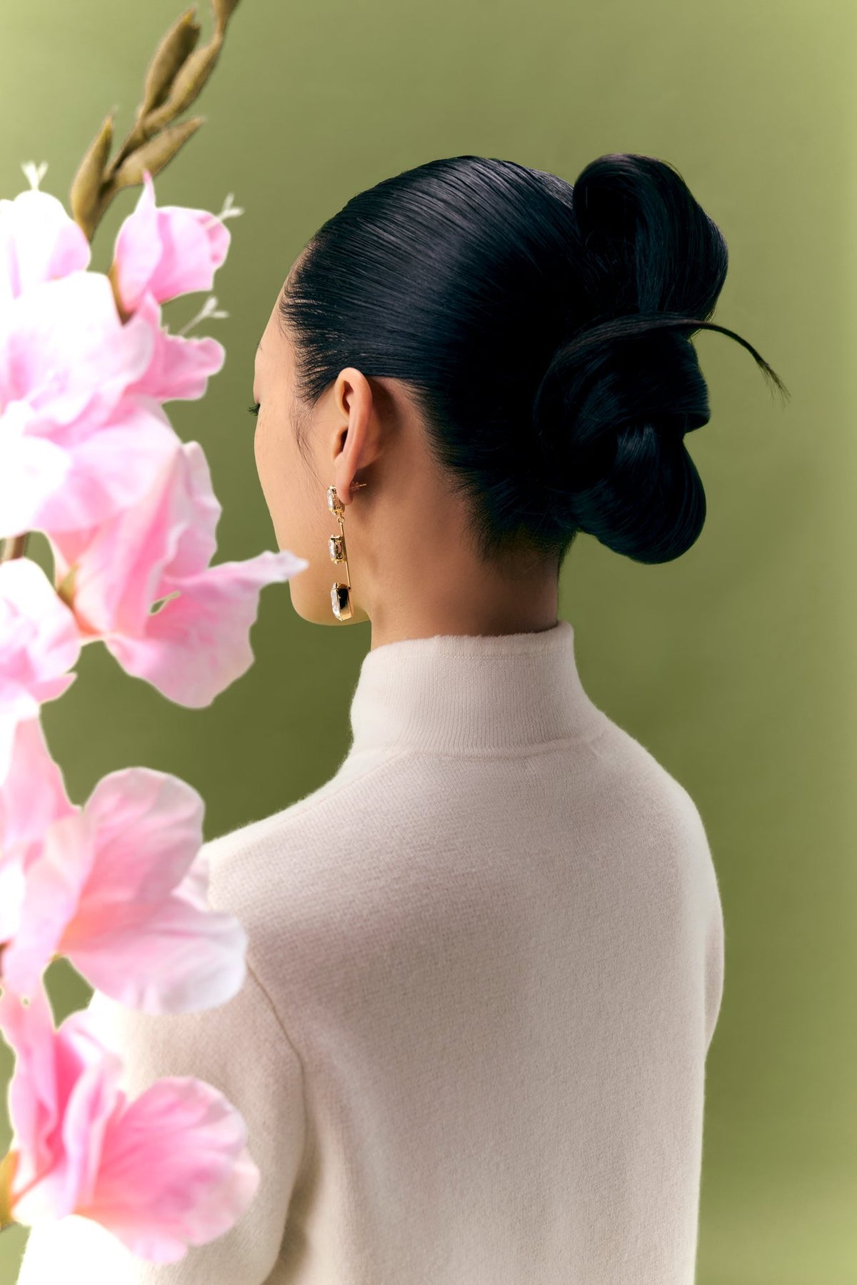 Woman in an ivory cashmere turtleneck beside pink blossoms