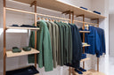 Green and navy cashmere knitwear hanging on a wooden rail in a GOBI store