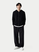 Person wearing a black hoodie and pants with white shoes on a white background. #color_black #ai-image