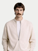 Man wearing a light beige bomber jacket over a white shirt on a plain background. #color_white #ai-image