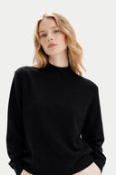 Woman wearing a black sweater against a plain background Gobi Cashmere #color_Black