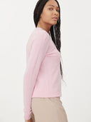 side view of a woman wearing a soft pink sweater and beige pants. #color_pink 